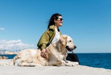 Woman and dog watching ocean from beach